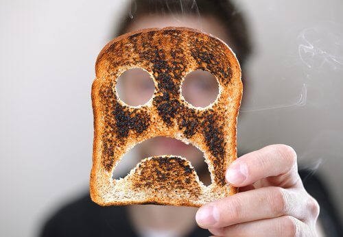Person der holder et stykke toastbroed med en sur smiley