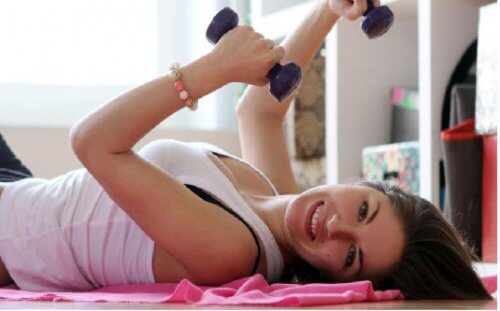 Ung kvinde der ligger paa gulvet og traener med vaegte