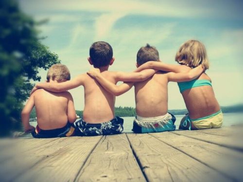 4 boern der sidder paa en badebro