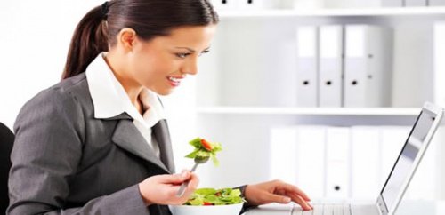 Kvinde spiser paa kontoret