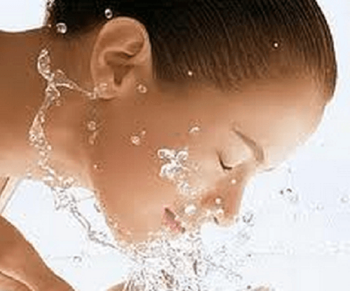 Kvinde der sproejter vand i ansigtet