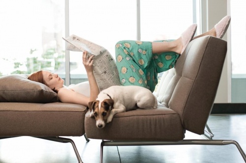 Kvinde der laeser paa en sofa