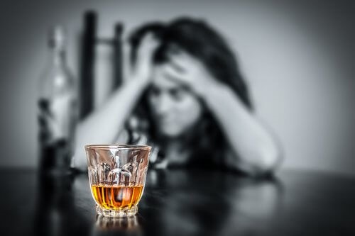 Kvinde der sidder ved bordet med et glas alkohol