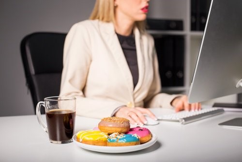 Kvinde der spiser donuts mens hun arbejder