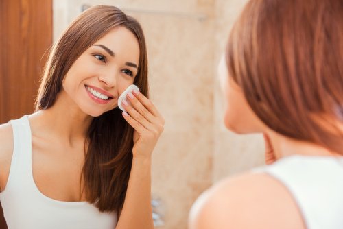 Kvinde der ser sig selv i spejlet mens hun ordner sin hud