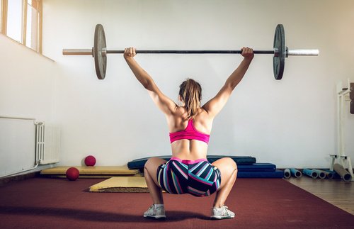 Kvinde der laver sumo squat med vaegtstang