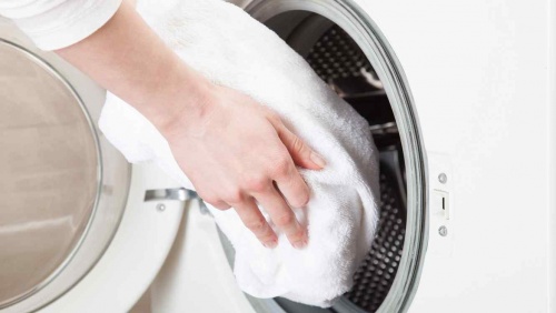 Kvinde der smider toej i vaskemaskinen