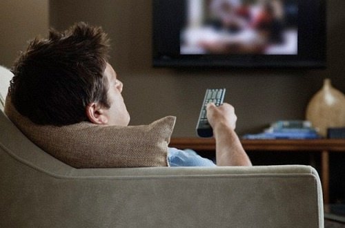 Mand der sidder i sofaen foran tv'et