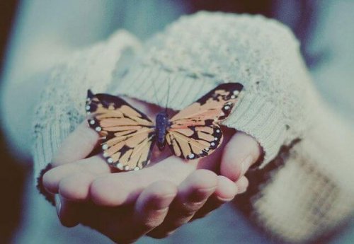Pige der holder en sommerfugl i haenderne