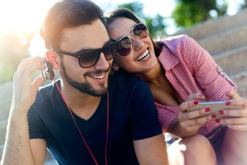 Par der sidder udenfor med en mobil og hoerer musik