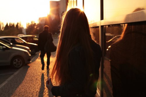 Ung kvinde der staar udenfor og kigger mod solen