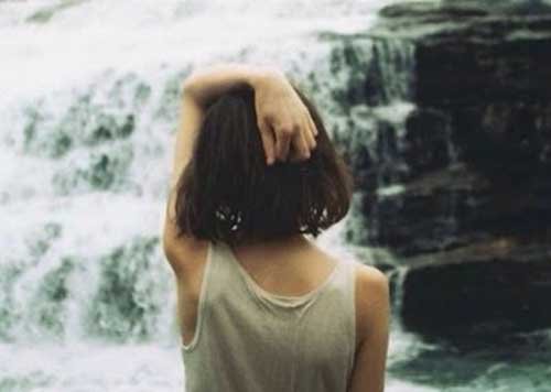 Pige der staar foran et vandfald