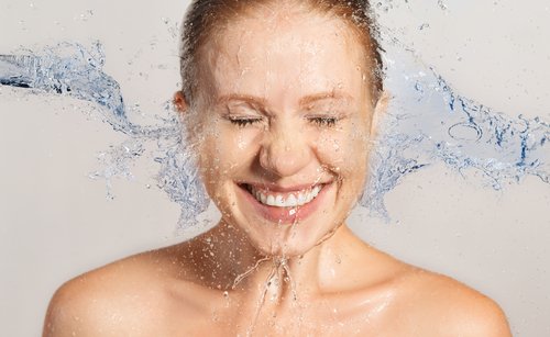 Kvinde der smiler med vand i ansigtet