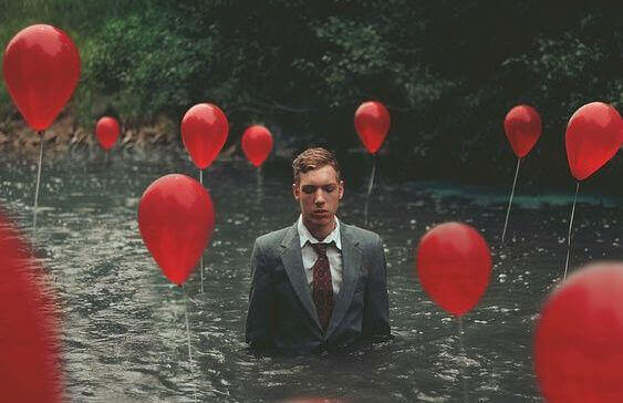 Man i jakkesaet i en flod omgivet af roede balloner