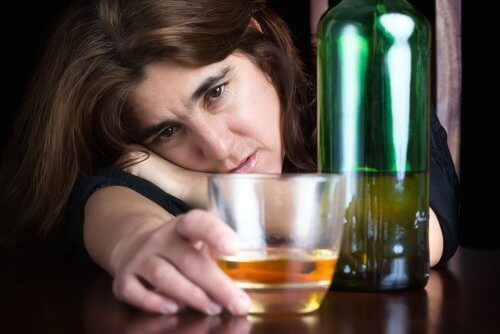 Kvinde der haenger over et glas alkohol
