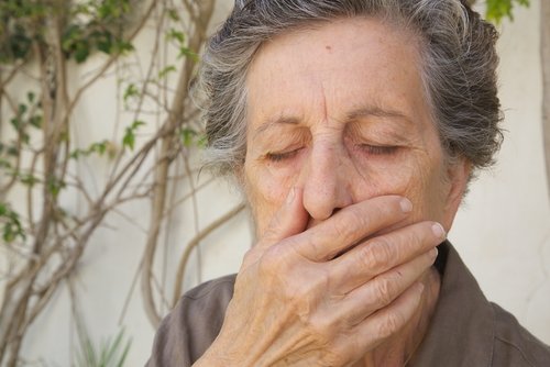 Aeldre kvinde der holder sig for munden