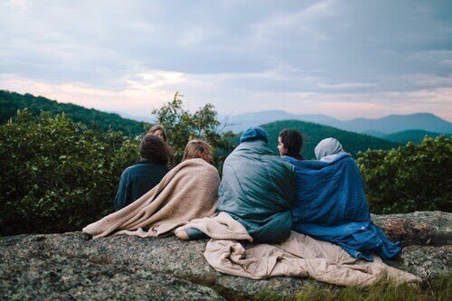 5 personer der sidder udenfor med taepper omkring sig