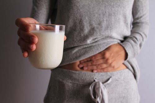 Kvinde med ondt i maven og et glas maelk