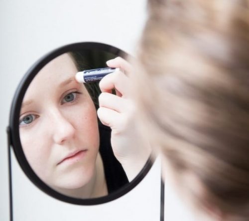 Pige der smoerer laebepomade paa sit oejenbryn