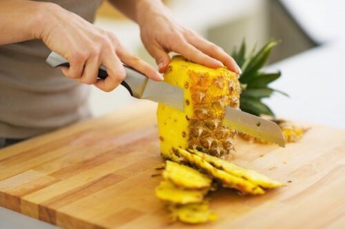 Person skærer ananas ud.
