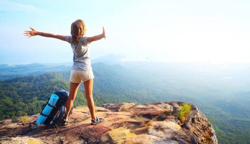 Kvinde der staar paa toppen af en klippe