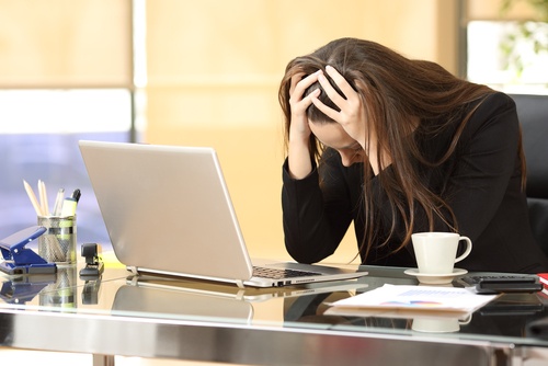 Kvinde på kontor tager sig til hovedet, fordi hun ikke kan overvinde stress