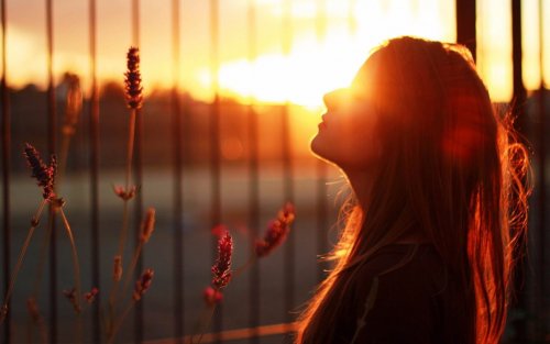 Kvinde der staar udenfor ved solnedgang