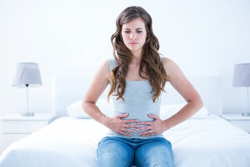 Kvinde holder sig til maven, fordi hun har ondt paa grund af tarmbakterier