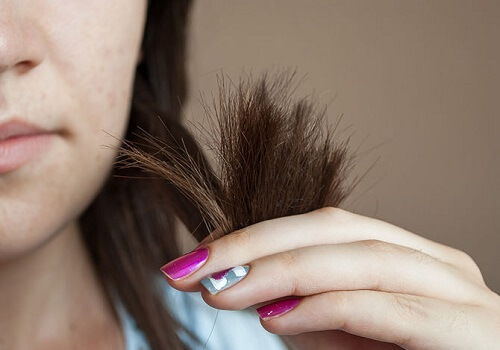 Kvinde der holder sit haar med en haand