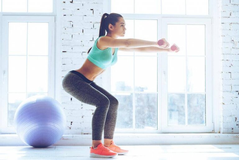 Kvinde der laver squats med haandvaegte