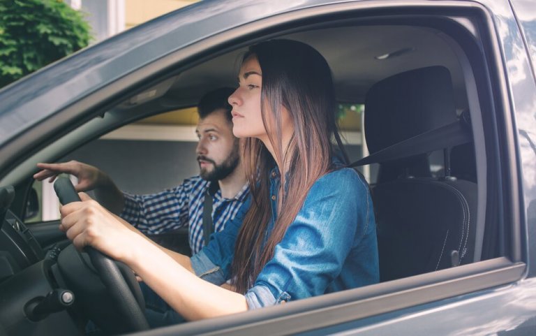 Kvinde der koerer bil med en mand som passager
