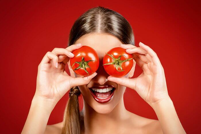 Kvinde der holder tomater for oejnene