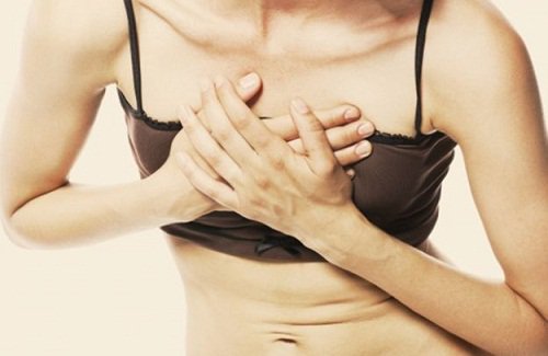 Kvinde der tager sig til brystet pga smerter