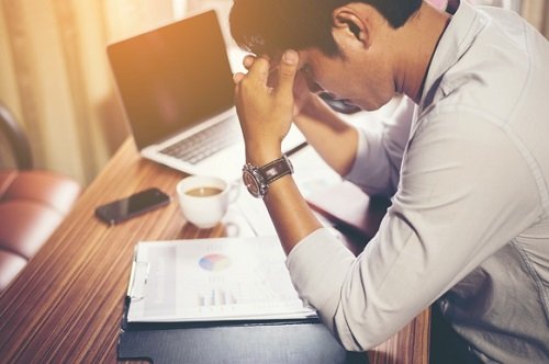 Mand med hovedpine paa arbejdet