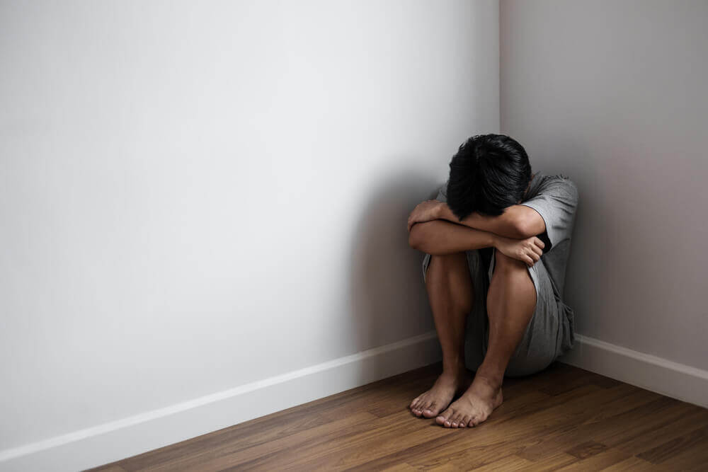Dreng der sidder i hjoernet og er ked af det - barn tager stoffer