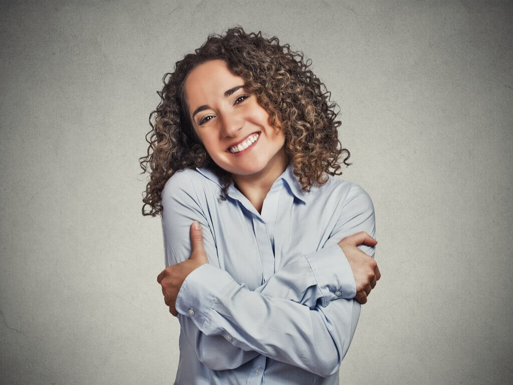 Kvinde der smiler og krammer sig selv