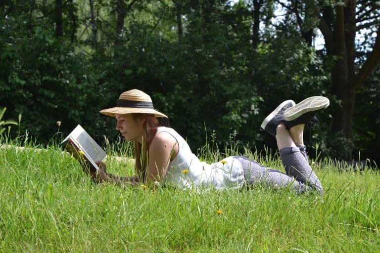 Kvinde der laeser i graesset - have en plante