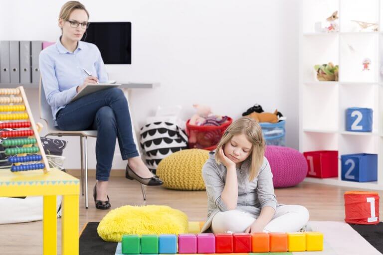 Pige der sidder paa gulvet med en kvinde bag sig