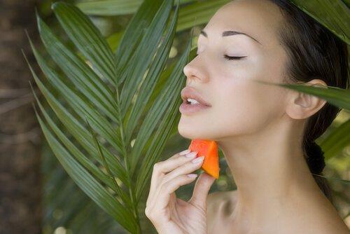 Kvinde der smoerer papaya paa sin hals