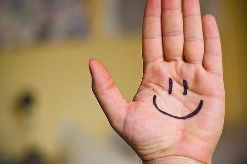 Flad haand der har en paategnet glad smiley