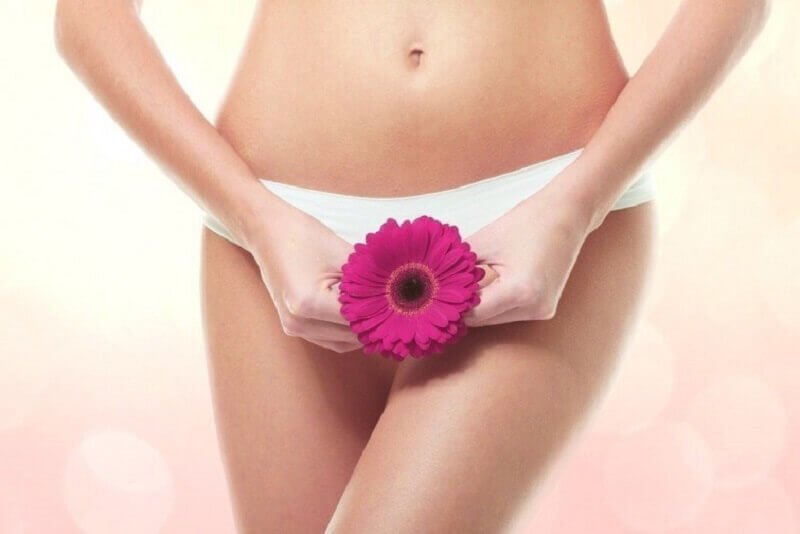 Kvinde der holder en blomst foran sine trusser