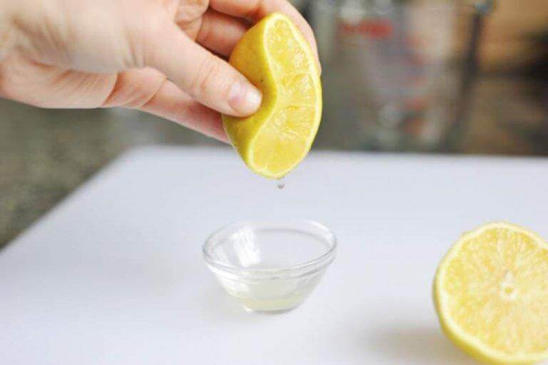 Hånd der presser citronsaft ud i en skål