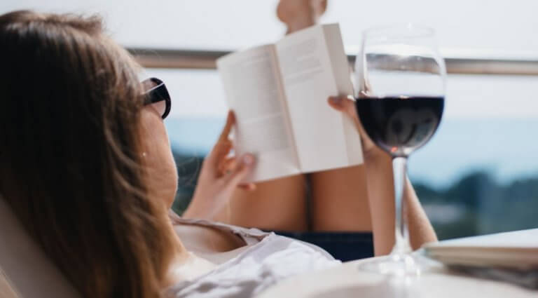 Kvinde laeser bog med roedvin