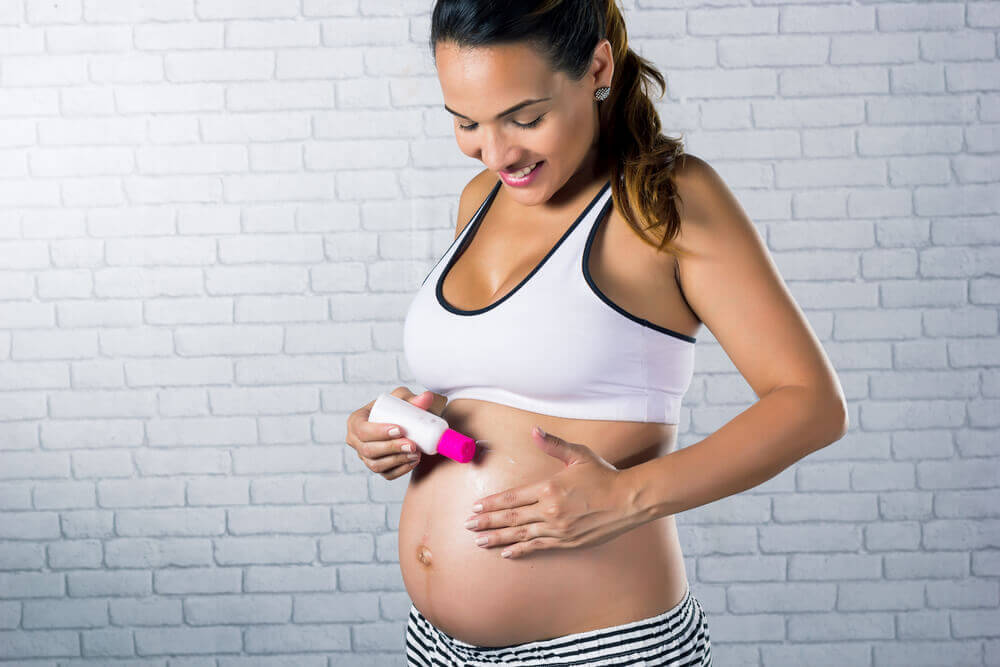 Kvinde smørrer sin gravide mave