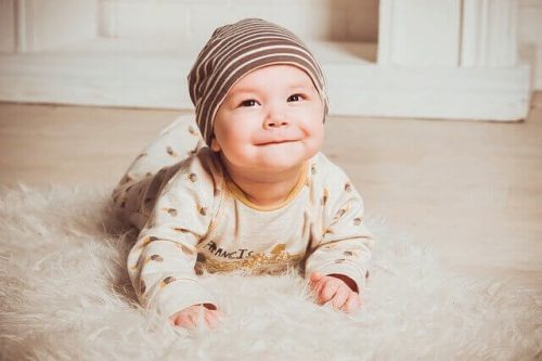 Baby der ligger paa gulvet og smiler