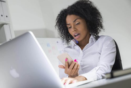 Forbavset kvinde kigger paa sin mobiltelefon