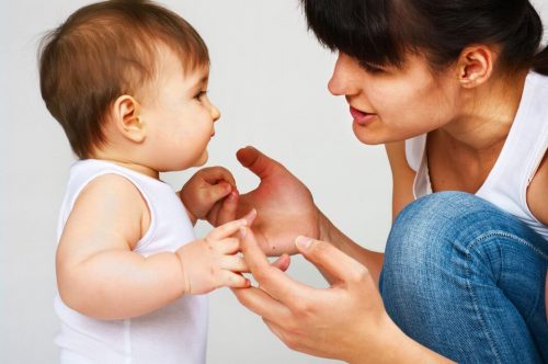 Mor sidder på hug og kigger sin baby i oejnene