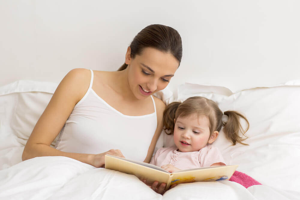 Kvinde læser højt for sit barn.