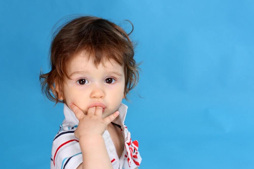 Lille barn med finger i mund.