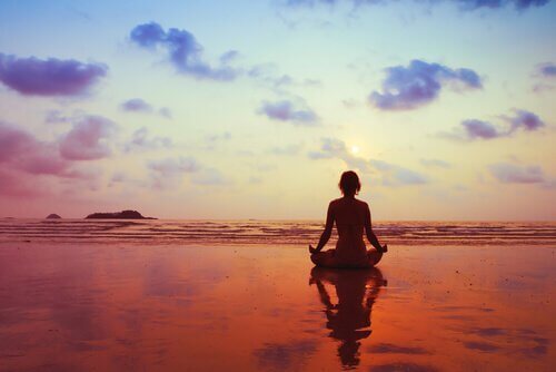 Kvinde mediterer på stranden